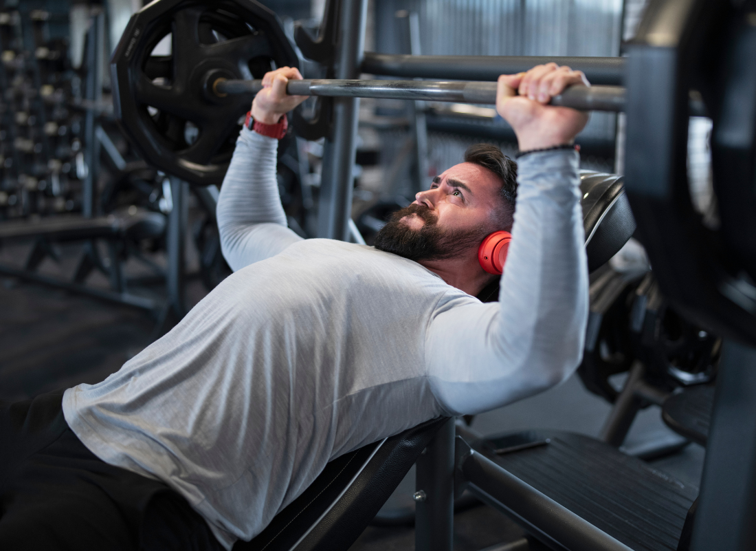 Man bench pressing weights with focus and determination in a gym